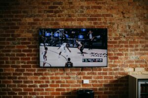 black flat screen tv mounted on brown brick wall