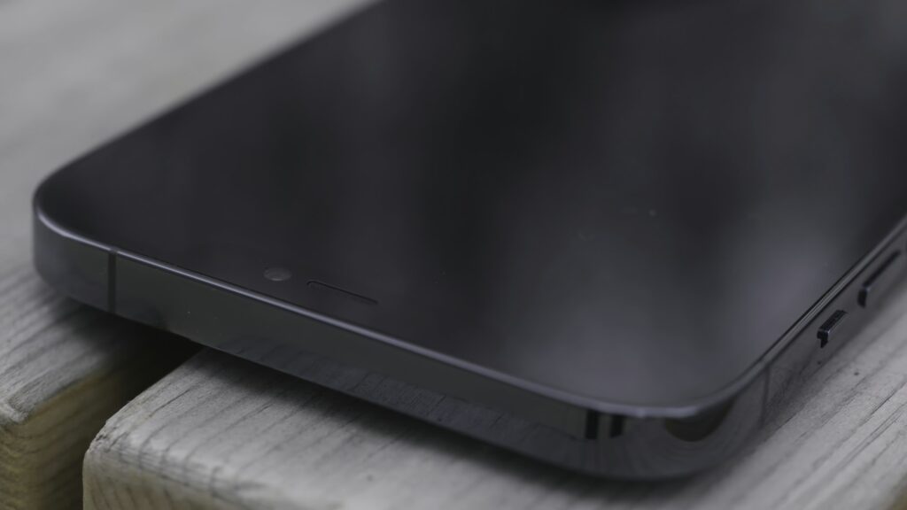 Close up of a part of a black screen of a new smartphone on wooden bench background. Action. New