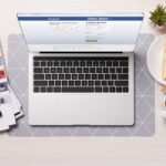 office desk with laptop with facebook website on screen, flat lay