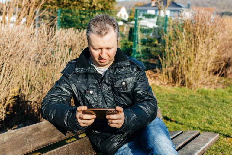 A man sits on a bench and uses a mobile phone. Wireless technologies. Communication at a distance
