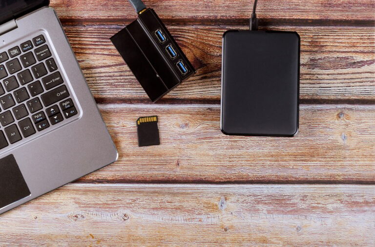 Photographers desktop workspace external backup disk hard drive connected to laptop computer