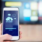 Comprendre pourquoi votre iCloud est grisé sur Mac, iPhone ou iPad et comment le rétablir ? Smartphone with cloud and sun icons and uploading line on display