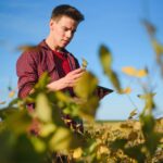Guide Vidéo : Comment Lire et Écrire sur un Disque NTFS depuis un Mac Young farmer in filed examining soybean corp at sunset.