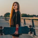 Longboard électrique : la révolution silencieuse qui transforme nos déplacements urbains Young woman holding her longboard