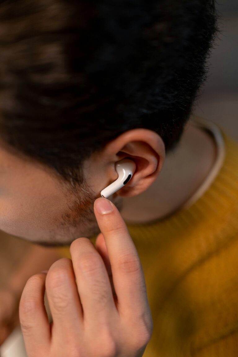 Close-up of a man wearing wireless earbuds in a yellow sweater, focusing on tech.