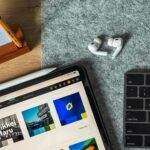A top view of a sleek workspace featuring an iPad, AirPods, and keyboard on a felt surface.
