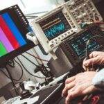 Technician operating laboratory electronic testing and measurement devices with colorful display.