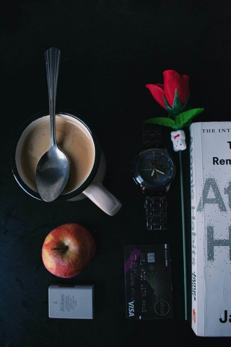 Apple Card : JPMorgan Chase remplace Goldman Sachs dans un tournant historique Flat lay featuring coffee, apple, book, watch, and a rose on a dark table.