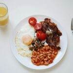 A mouth-watering breakfast featuring bacon, beans, egg, and orange juice.