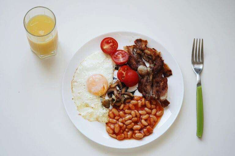 A mouth-watering breakfast featuring bacon, beans, egg, and orange juice.