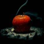 A striking image of a red apple with smoke emanating against a black background.