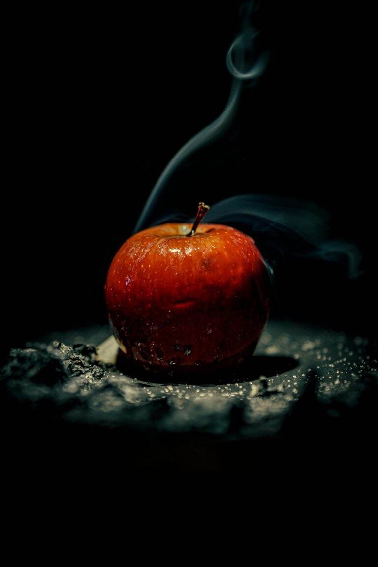 A striking image of a red apple with smoke emanating against a black background.