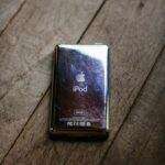 Classic iPod 30GB with a reflective surface on a rustic wooden floor.