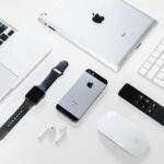 Flat lay of Apple devices including iPhone, iPad, MacBook, and Watch on a white surface, ideal for tech enthusiasts.