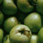 Tiny transparent drops on bunch of fresh green apples with short stems in daytime