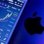 Pourquoi l'action Apple surpasse le marché malgré la chute du secteur technologique A close-up of an Apple device displaying stock market graphs, indicating economic trends.