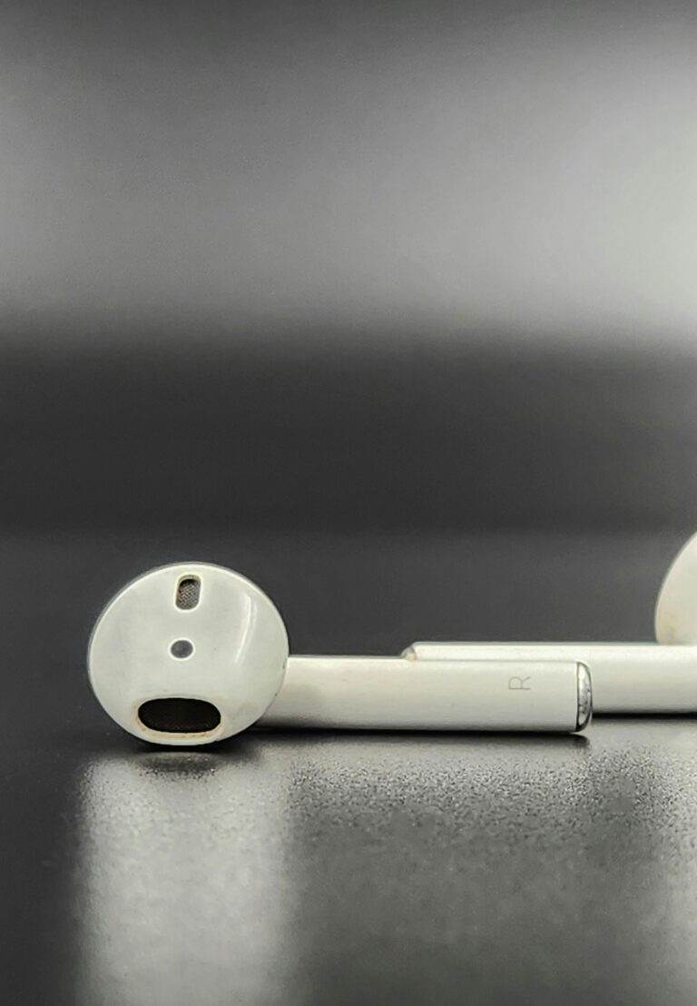 Minimalist close-up photo of Apple AirPods on a dark surface, highlighting sleek design.