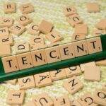Apple et Tencent concluent un accord autour d'une commission de 15% sur les achats des mini-jeux WeChat Wooden Scrabble tiles arranged to spell 'Tencent' on a green tile holder, scattered letters in the background.