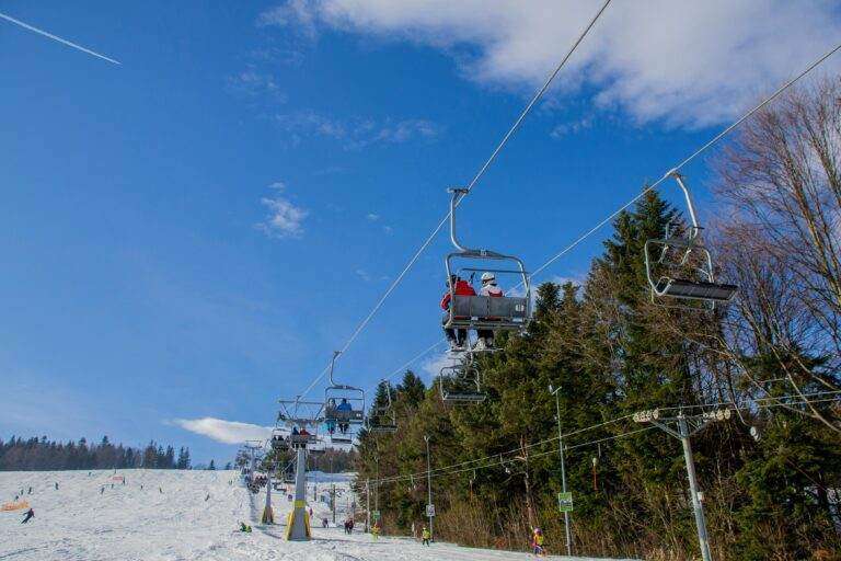 A ski lift carrying people over a snowy slope on a clear sunny day, perfect for winter sports.