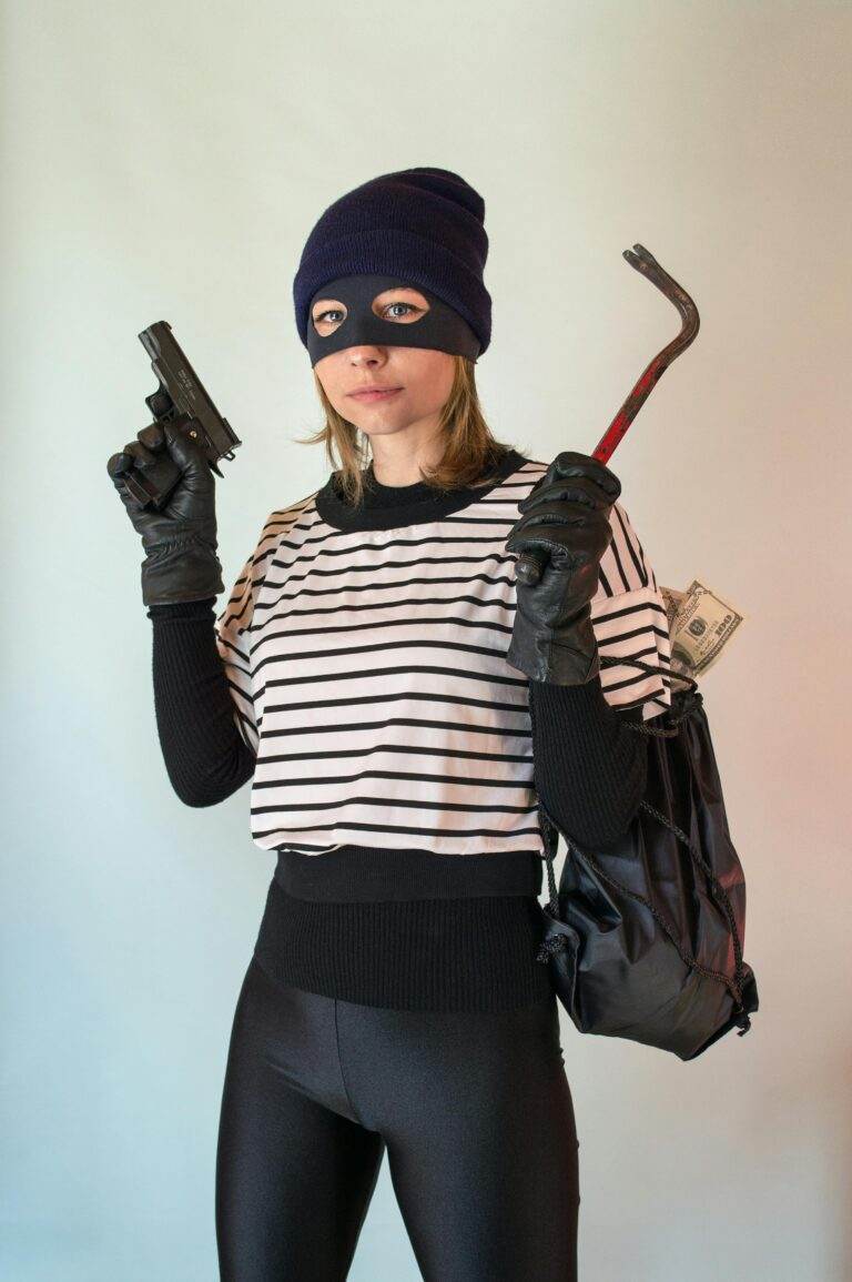 Woman posing as a thief holding a gun and crowbar with a bag of money.