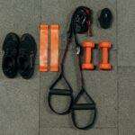 Flat lay of fitness gear including dumbbells, sneakers, and resistance bands for a home workout.