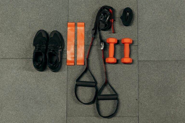 Apple Fitness+ frappe fort en 2026 : programmes inédits, défi Strava et badges pour transformer vos résolutions en habitudes Flat lay of fitness gear including dumbbells, sneakers, and resistance bands for a home workout.