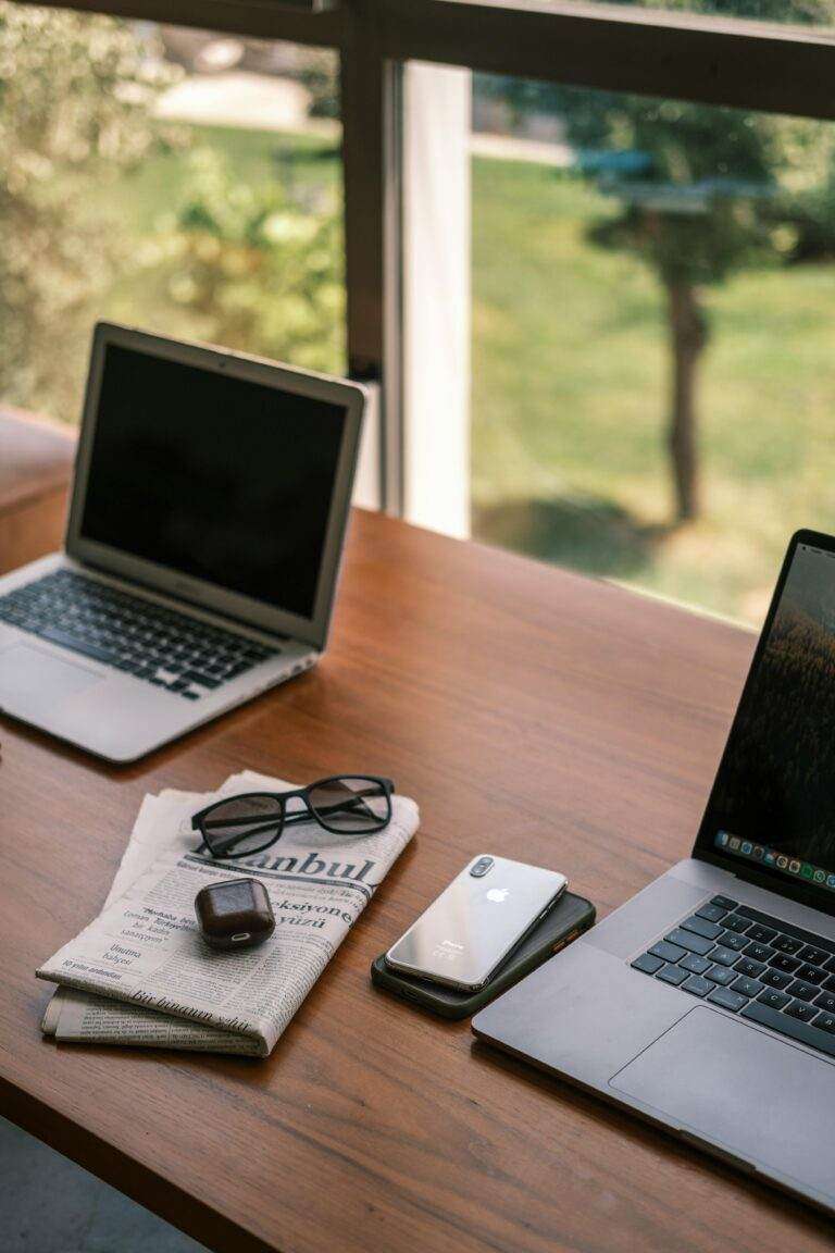 A stylish indoor workspace featuring laptops, smartphone, and accessories on a wooden desk.
