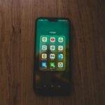 A smartphone showcasing various Google apps on a wooden table.