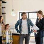 Family with child talks to real estate agent in modern kitchen during home showing.