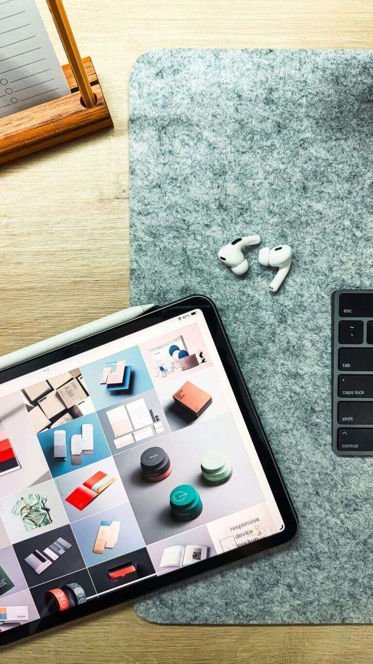 Flat lay of an iPad, AirPods Pro, and keyboard for a tech-savvy workspace setup.