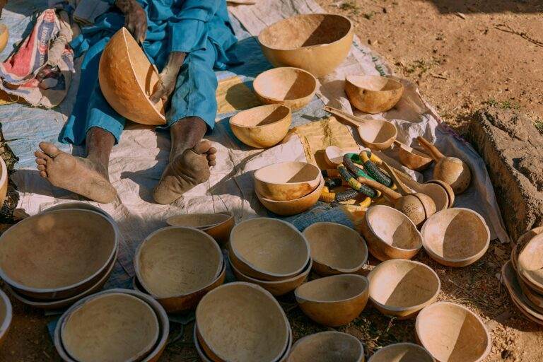 Authentic Nigerian artisan crafting calabash bowls outdoors, showcasing traditional craftsmanship and cultural heritage.