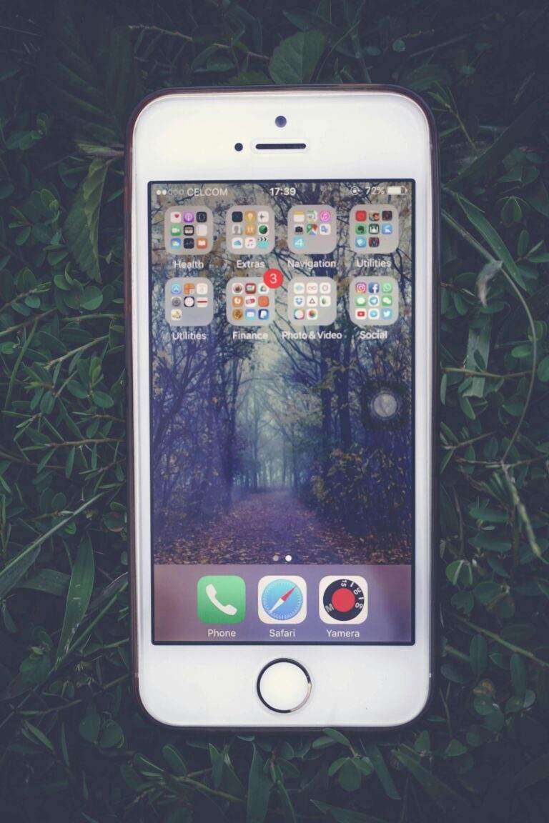 Les 3 Meilleures Applications iPhone de l’Année, Sélectionnées par Apple iPhone resting on grass, showcasing a forest wallpaper on its screen, symbolizing technology meets nature.