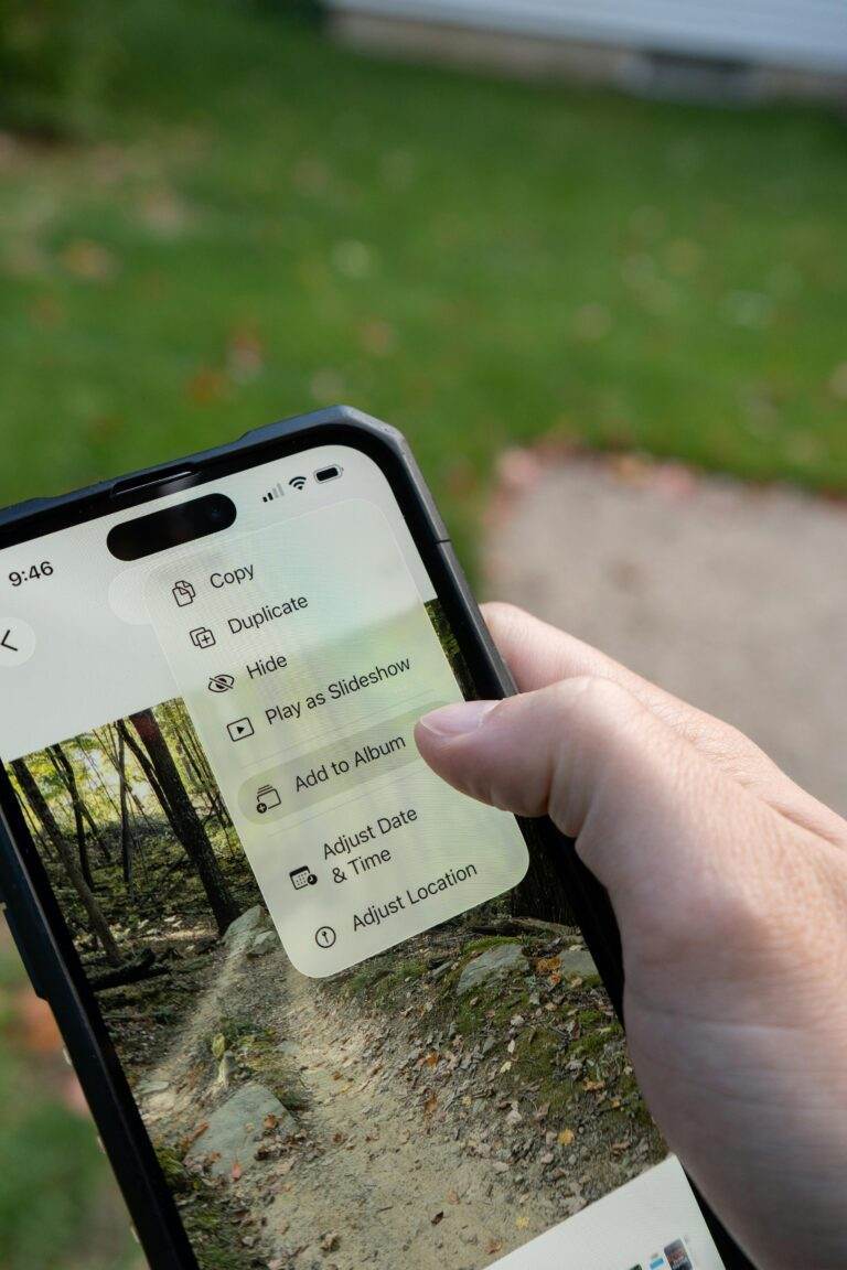 A person navigating photo management options on a smartphone outdoors.