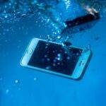 A smartphone immersed underwater amidst bubbles, creating a dynamic visual effect.