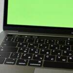 Le MacBook A18 Pro à 700 dollars : Apple frappe fort en 2026 Russian keyboard MacBook Pro with a green screen. Modern electronic device.