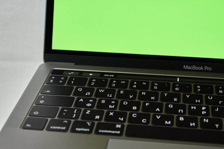 Le MacBook A18 Pro à 700 dollars : Apple frappe fort en 2026 Russian keyboard MacBook Pro with a green screen. Modern electronic device.