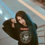 Portrait of a fashionable woman with blue hair wearing a Ramones T-shirt in an urban environment.