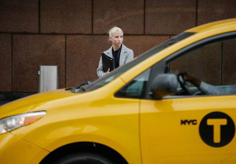Confident businesswoman stands by a New York City yellow taxi, epitomizing urban professionalism.