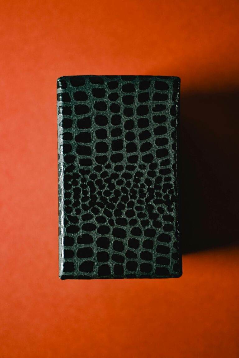 Close-up of a textured black leather box on a vibrant orange background, showcasing elegance and style.