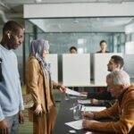 A diverse group of adults engaged in voting at an indoor polling station.
