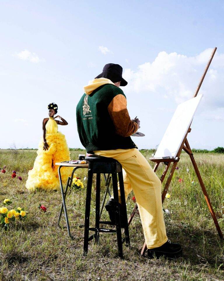 Artist painting a model in a yellow dress outdoors with flowers in Lagos, Nigeria.