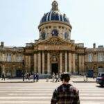 Tesla Robotaxi : une arrivée en France prochainement ? Front view of the historic Institut de France with people crossing the street in Paris.