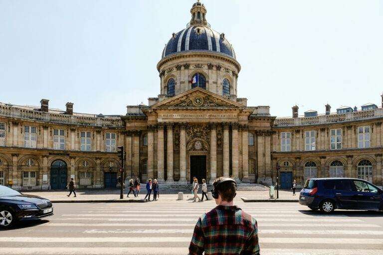 Tesla Robotaxi : une arrivée en France prochainement ? Front view of the historic Institut de France with people crossing the street in Paris.