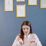 Apple doit révolutionner Siri avec l'IA pour inciter les utilisateurs d'iPhone plus anciens à passer à la dernière génération A woman wearing a headset having an online meeting, with certificates framed on the wall behind.