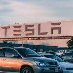 Tesla en quête d'intégration : vers un support d'Apple CarPlay dans ses véhicules Tesla factory with parked cars during sunset, showcasing modern automotive industry vibes.