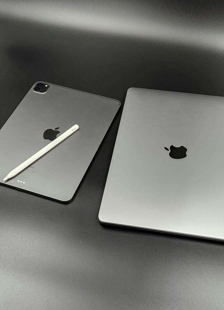 A stylish composition featuring a sleek Apple iPad and MacBook paired with an Apple Pencil on a modern black background.