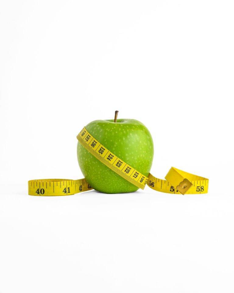 A vibrant green apple encircled by a yellow measuring tape, set against a clean white background.