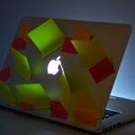 A glowing laptop with sticky notes attached, highlighting busy workspace or reminders.