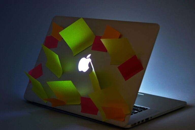 A glowing laptop with sticky notes attached, highlighting busy workspace or reminders.