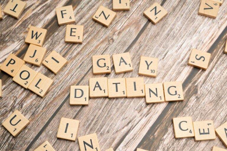 Scrabble tiles spelling 'Gay Dating' on a rustic wooden background, representing LGBTQ themes.